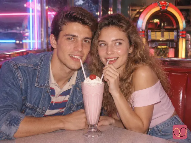 1980s couple photo — A couple shares a strawberry milkshake in a retro American diner